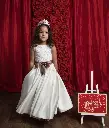 Sleeveless satin A-line ball gown with a pearl flowered lace top, fronted bow belt and decorated colour tail panel