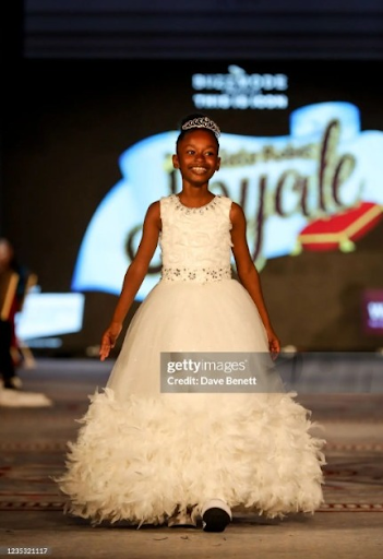 Sleeveless 3D floral lace ball gown with full princess skirt finished with faux feathers and hand embroidered gem belt